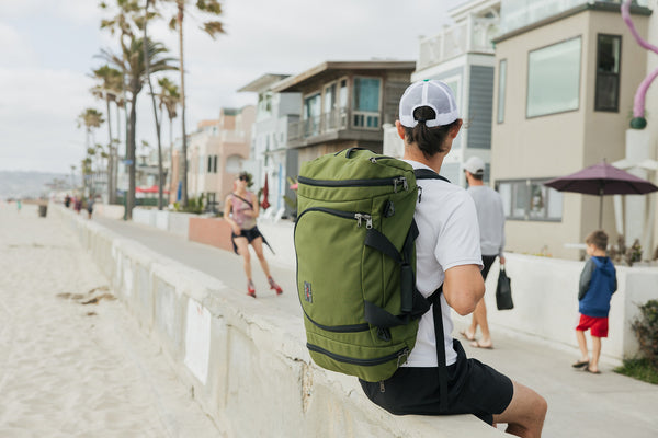 Person carrying an Aeronaut 45 sitting on the wall at the Venice Beach, CA boardwalk.
